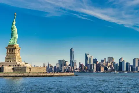Statua Wolności i panorama Manhattanu nad wodą.