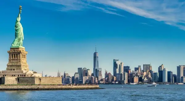 Statua Wolności i panorama Manhattanu nad wodą.